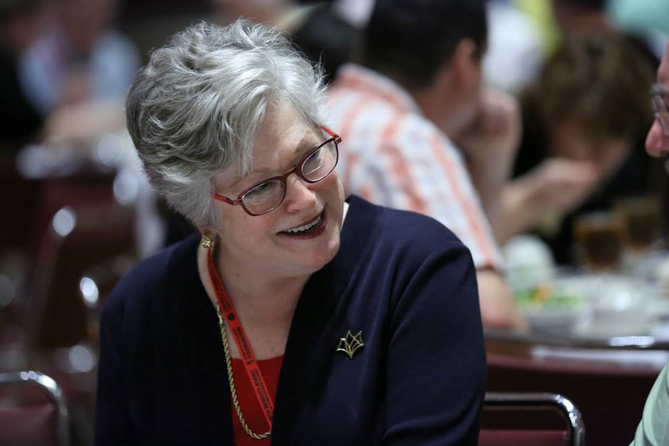 Molly Marshall smiling and visting with people at a meal