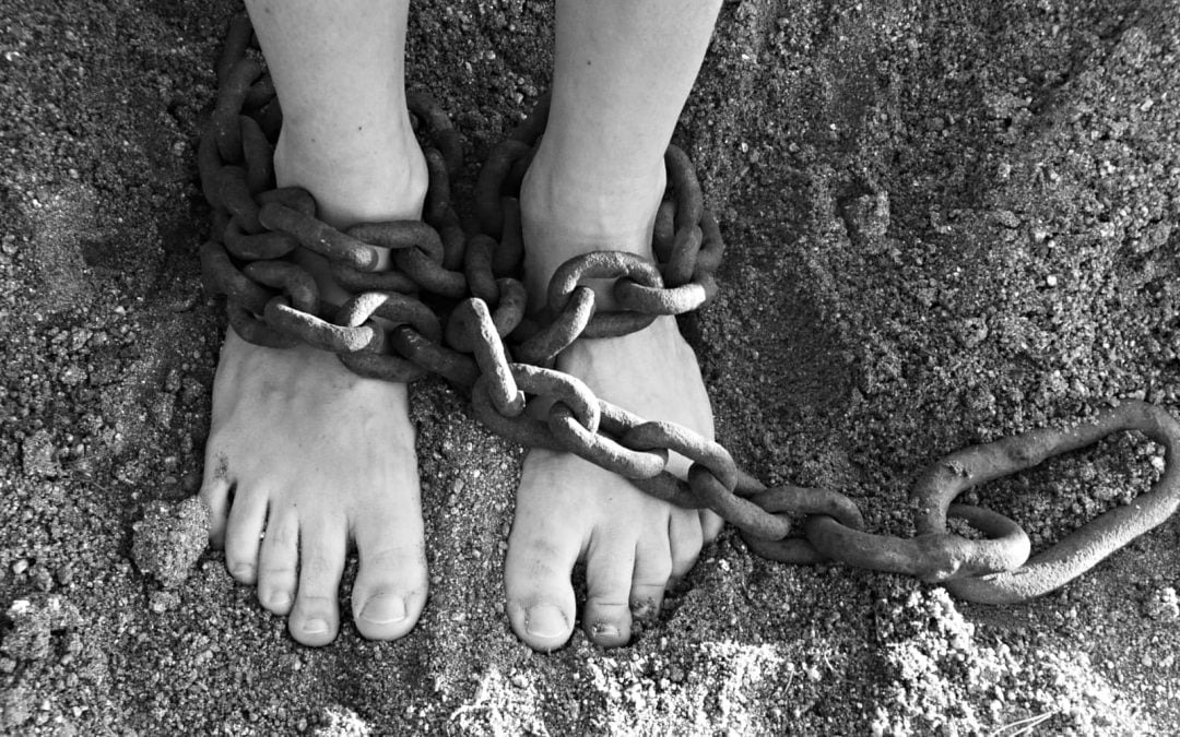 A person's feet on sand wrapped in chains