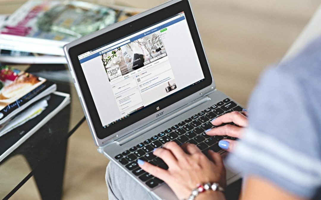 A woman using a laptop to access Facebook