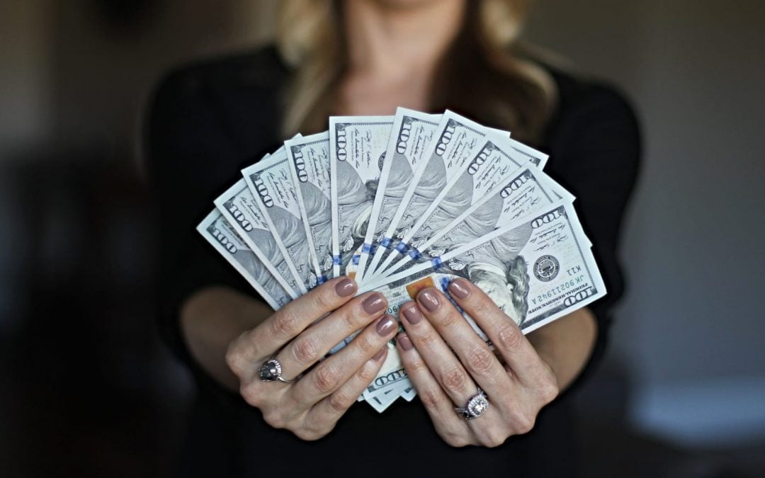 A woman holding $100 bills fanned out