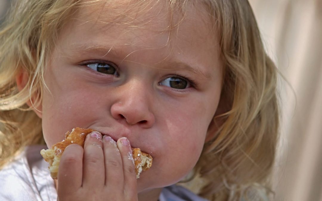 A young girl eating a piece of bread