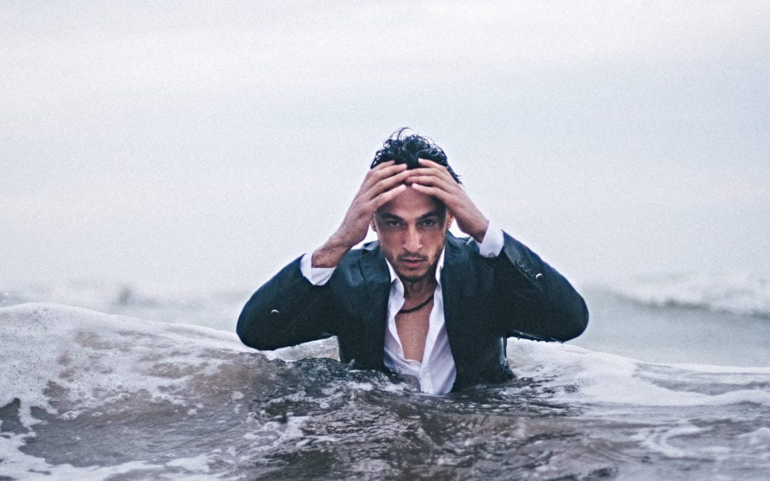 A man in a suite standing in the ocean