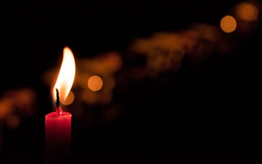 A single red candle lit in a dark room