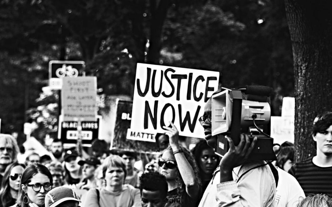 A group of protesters holding a sign that says justice now