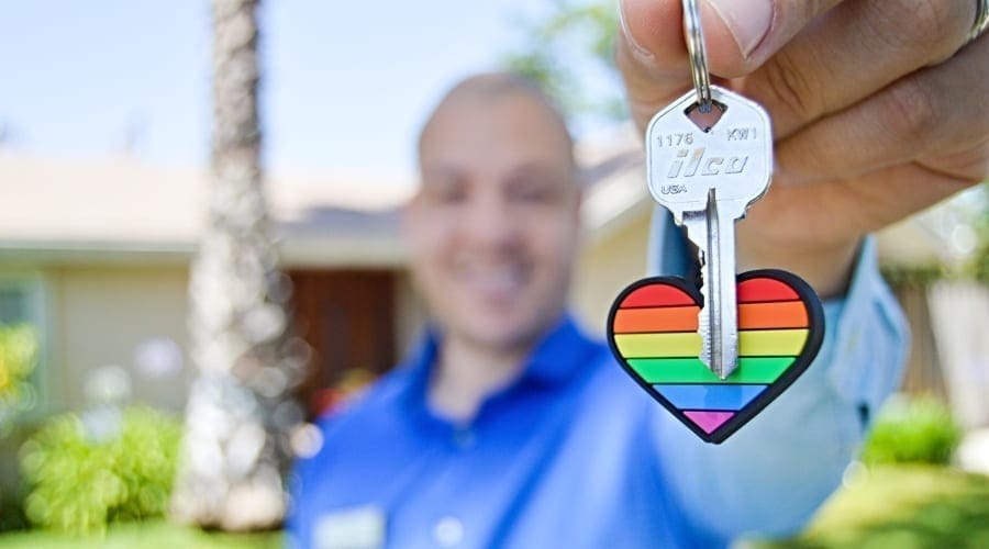 Man holding chain with key and rainbow-colored heart