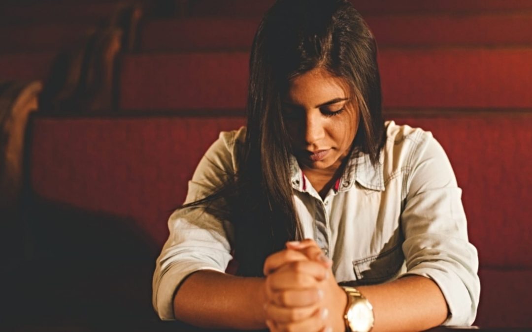 Woman praying in church pew