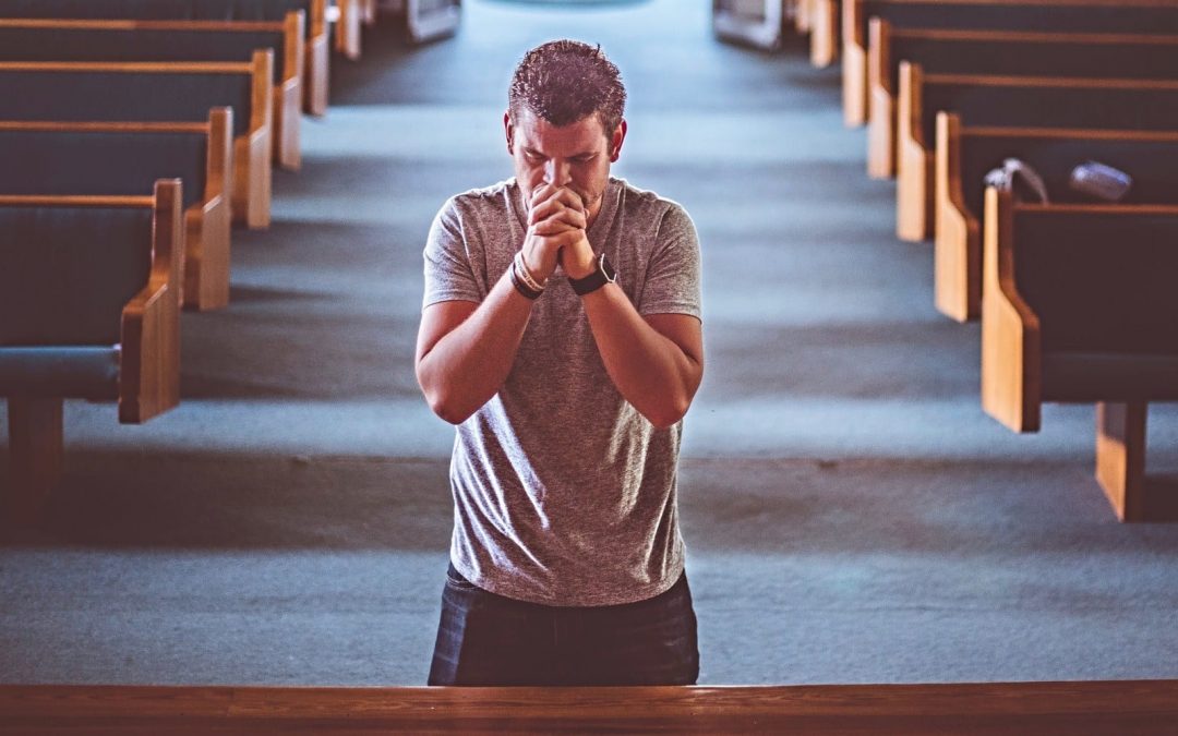 Man genuflecting and praying inside church sanctuary