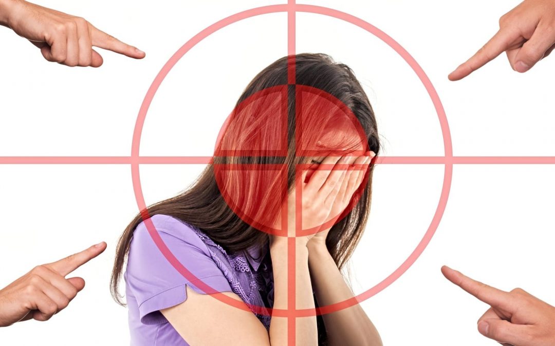 Woman in crosshairs with four hands pointing at her