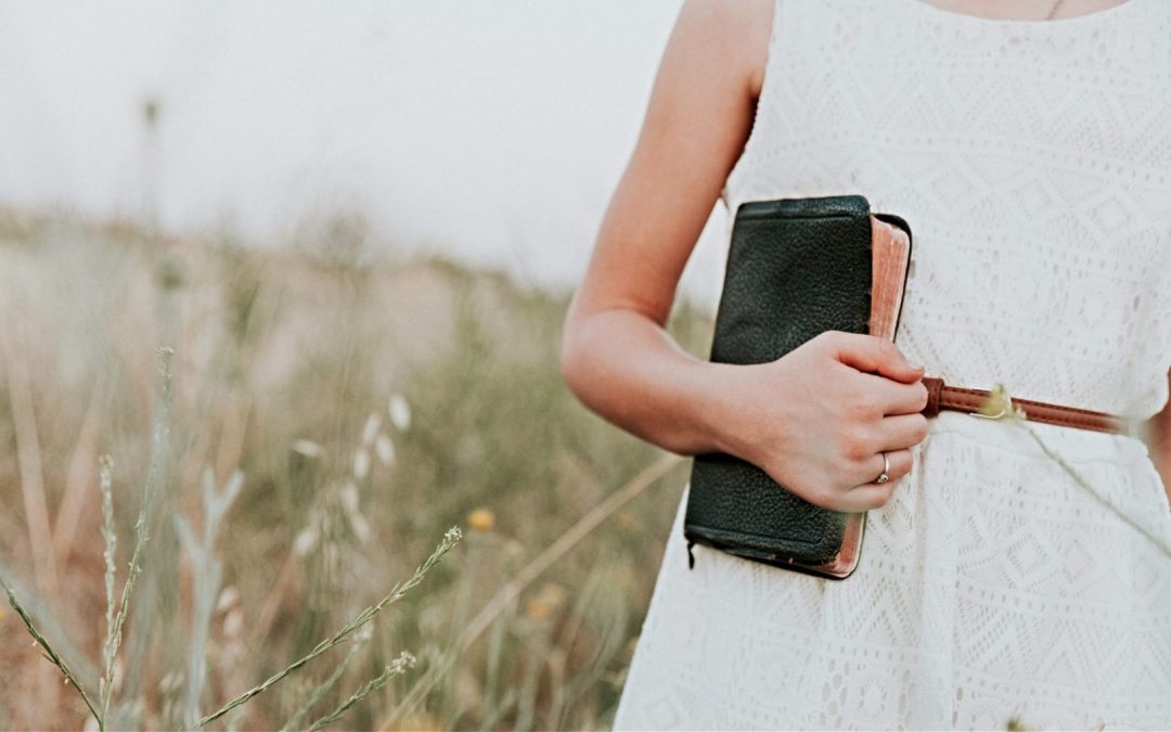 Woman holding Bible in field