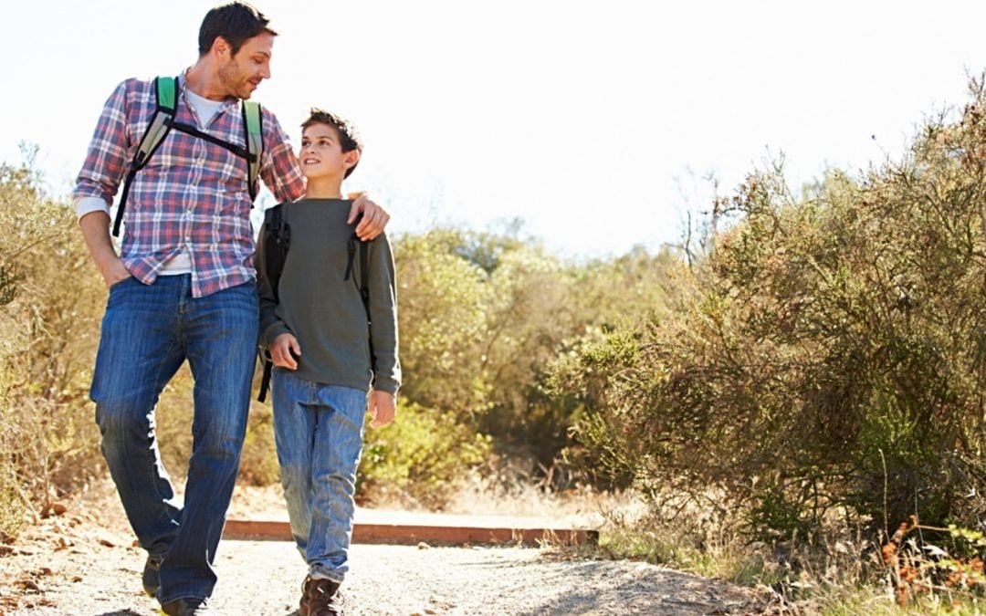 Father and son walking on trail on sunny day