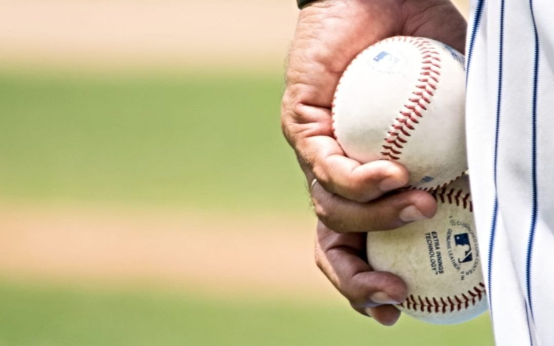 Uniformed pitcher holding two baseballs