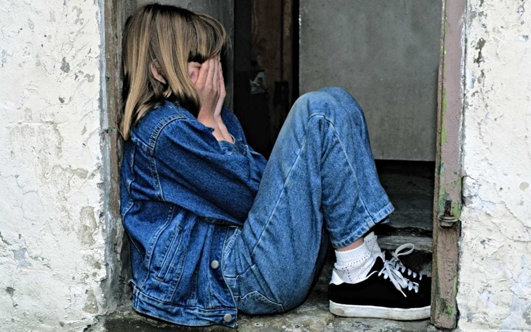 Girl sitting in doorway, alone and crying