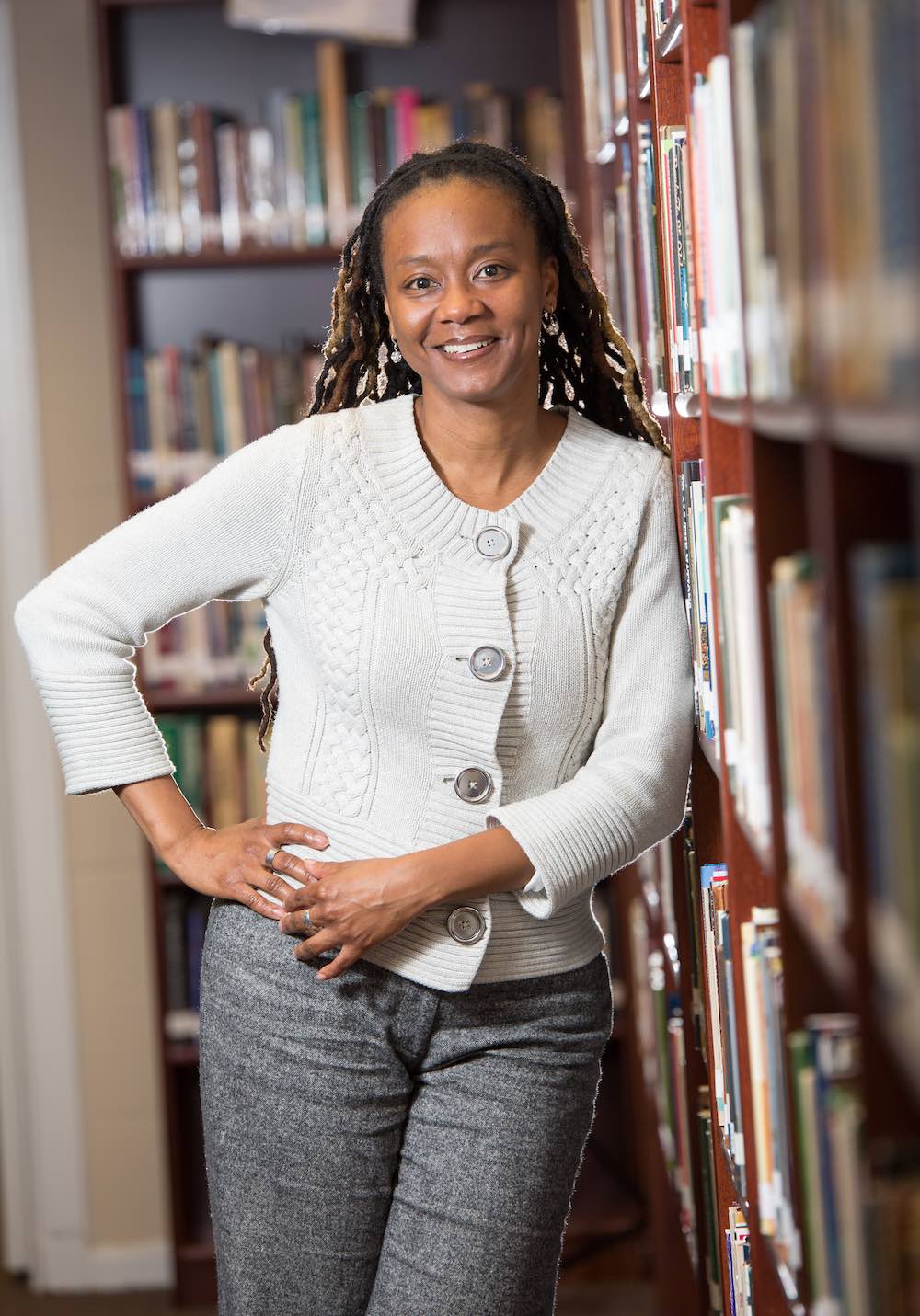 A woman standing next to a bookshelf.